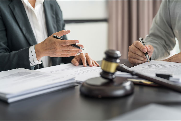 People at a desk reviewing legal documents with a judge’s gavel visible